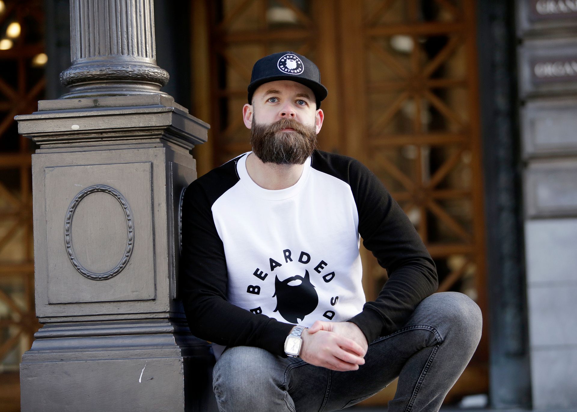 Man in White and Black Pullover Shirt Leaning on Black Post