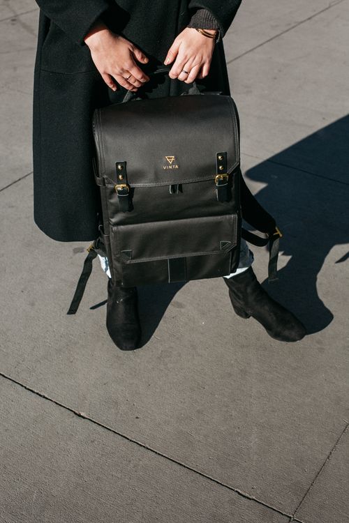 Free Fashionable black backpack held by a person on a city pavement in daylight. Stock Photo