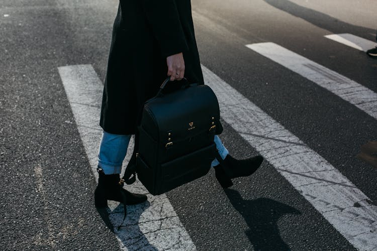 Person Carrying Bag Walking On Pedestrian Lane