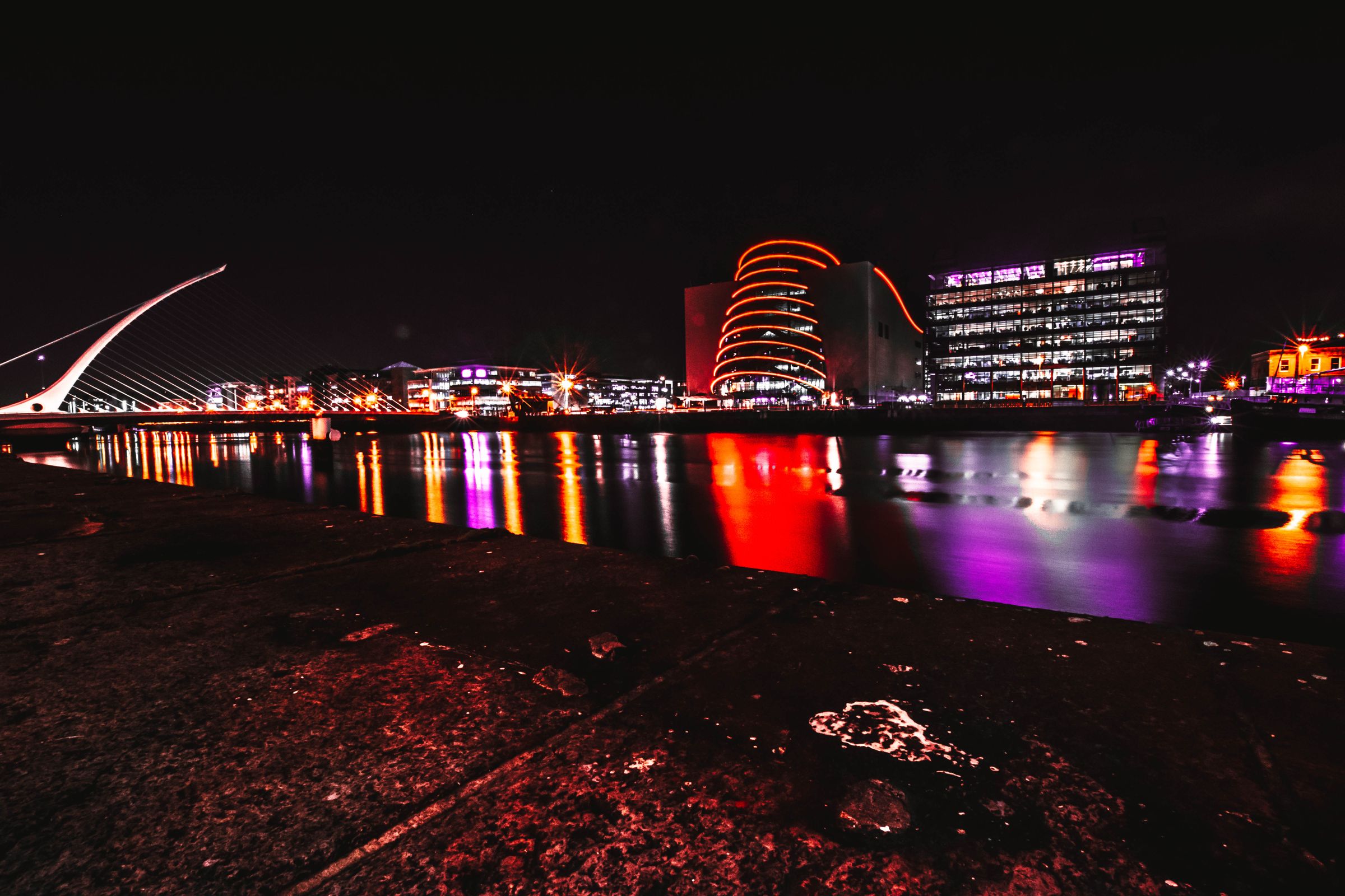 A night scene capturing the illuminated Dublin cityscape with reflections on the river
