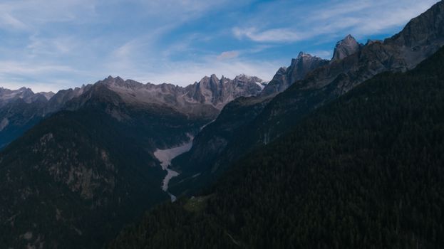 A stunning aerial view of the rocky mountain range under the blue sky, captured at dusk.