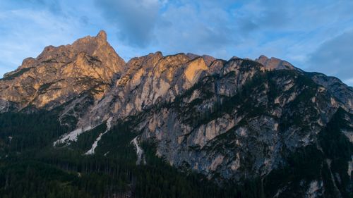 Free Scenic view of a majestic rocky mountain peak illuminated by twilight sun under a blue sky. Stock Photo