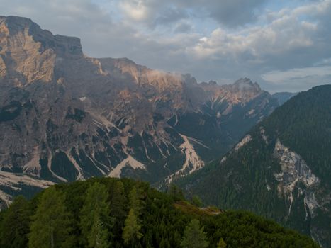 Stunning aerial photo capturing rocky mountain peaks and lush green valleys under a cloudy sky.