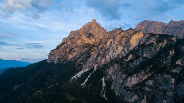 Capture the awe-inspiring view of rocky mountains under a blue sky at twilight.