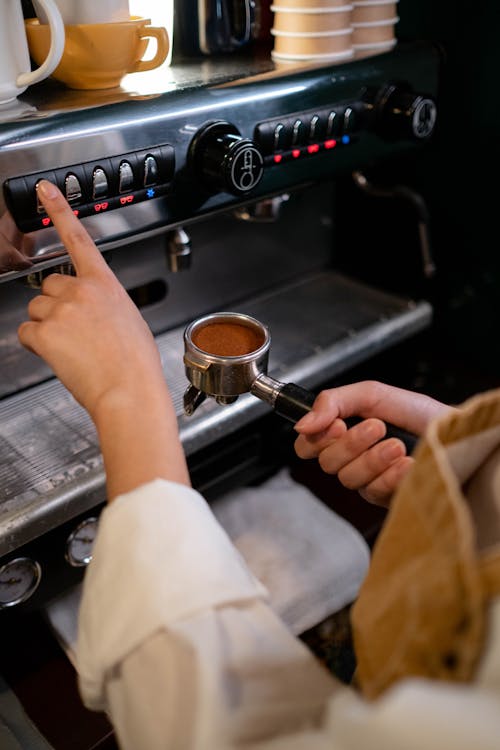 A Person Holding a Portafilter while Using a Coffee Machine
