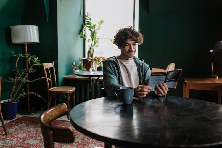 A Man Reading A Book At A Coffee Shop