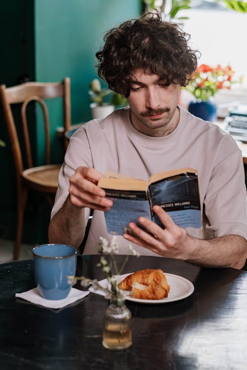 A Man Reading a Book on a Table 