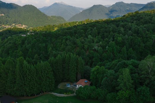 Aerial view of a lush forest and mountains with a secluded house.