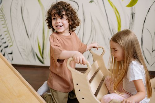 Free Two young children enjoy a fun and playful moment indoors with a wooden toy in a creative playroom setting. Stock Photo
