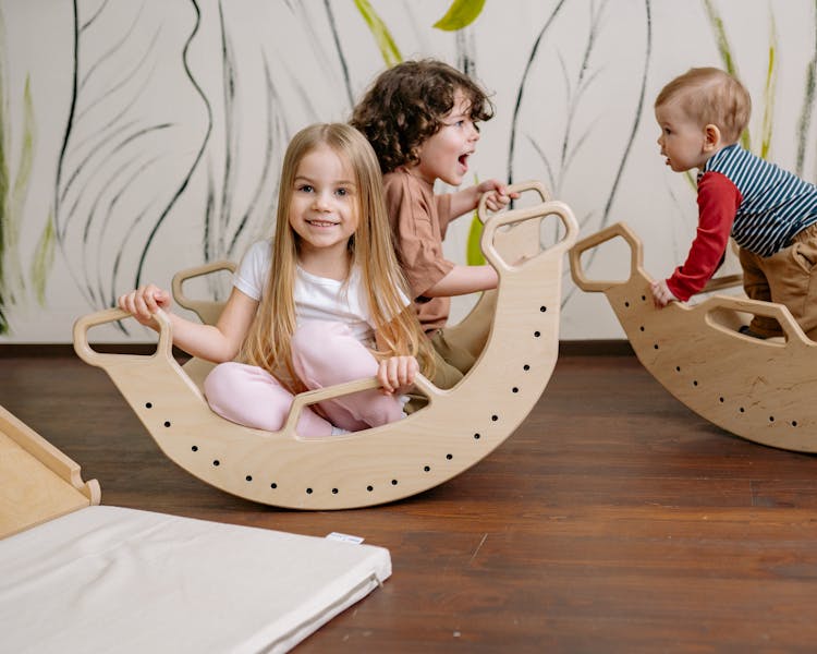 Young Kids Sitting On A Wooden Rockers