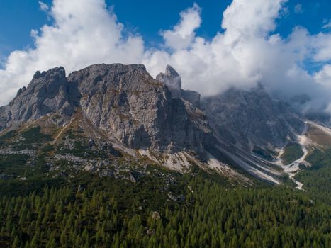 A breathtaking aerial view showcasing rugged mountains surrounded by lush forests and a vibrant blue sky.