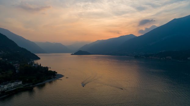 Aerial view of a tranquil lake with mountains and a picturesque sunset sky.