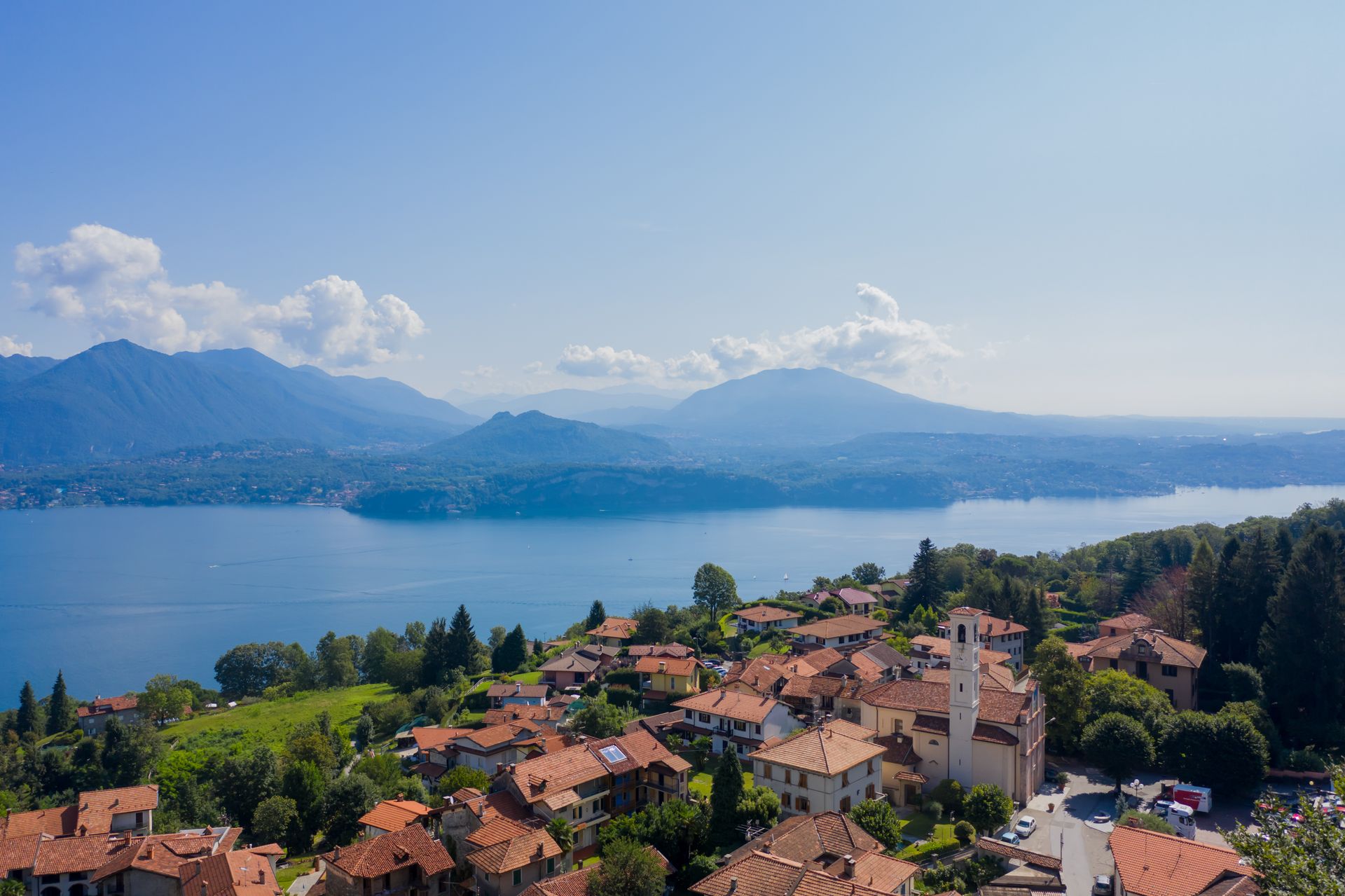 A picturesque aerial view of a village by a lake with mountains in the distance, showcasing rural beauty.