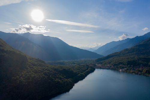 Free A stunning aerial photo of a tranquil lake surrounded by lush mountains under the bright sun. Stock Photo