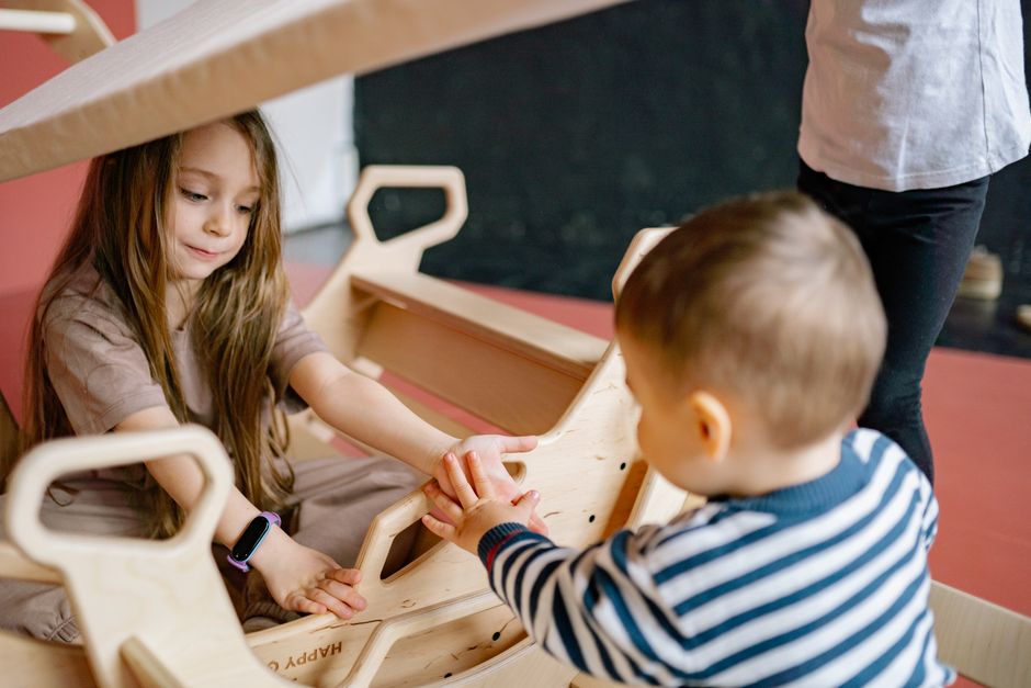 Photo by Yan Krukau on Pexels Children enjoying a playful moment with a wooden rocker indoors, emphasizing fun and interaction. - Photo by Yan Krukau on Pexels