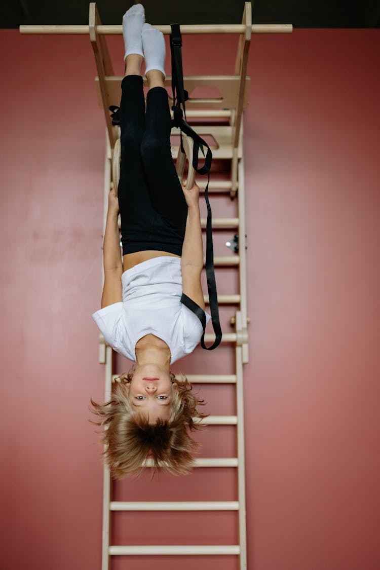 A Boy Hanging Upside Down On Gymnastics Ring