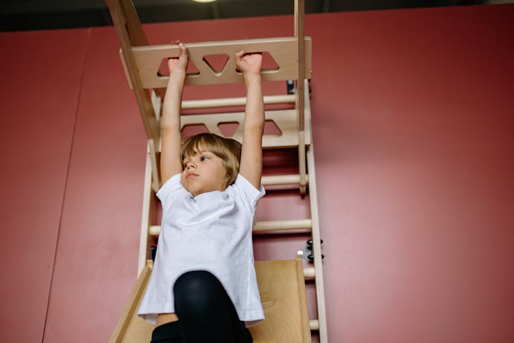 Child Hanging On A Wood Ladder