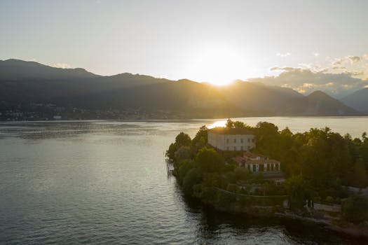 A beautiful sunset over a tranquil lake with mountains and lush greenery.