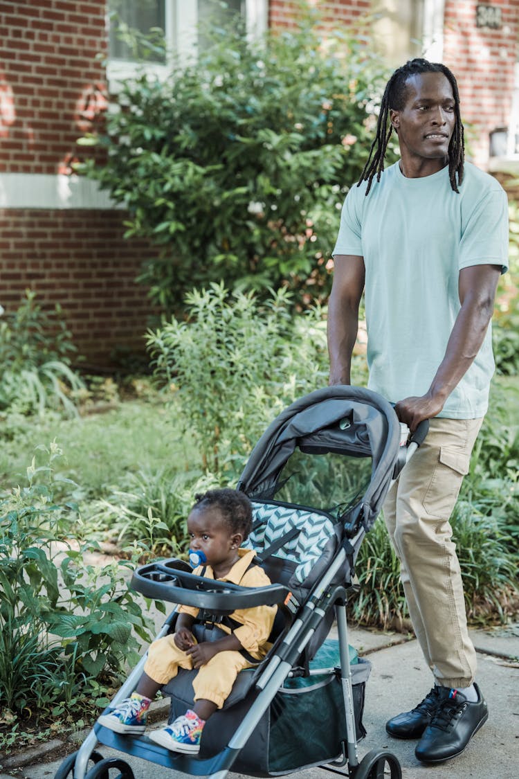 Man Pushing A Child In A Baby Stroller