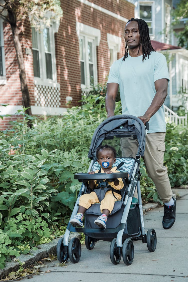 Man In A Green Shirt Pushing A Child In A Stroller