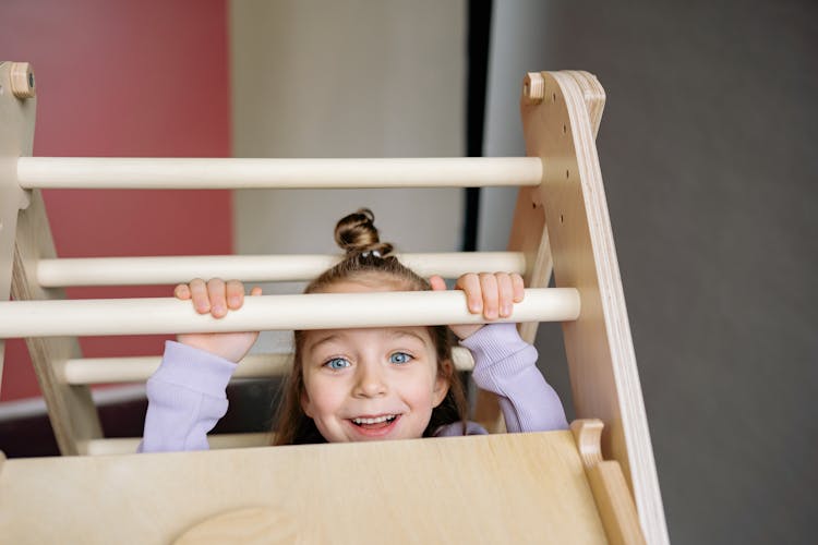 Young Girl Playing On A Wooden Climbing Frame