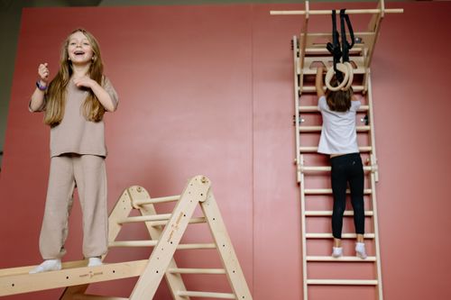 Free Two children playing on wooden indoor climbing equipment with joy and excitement. Stock Photo