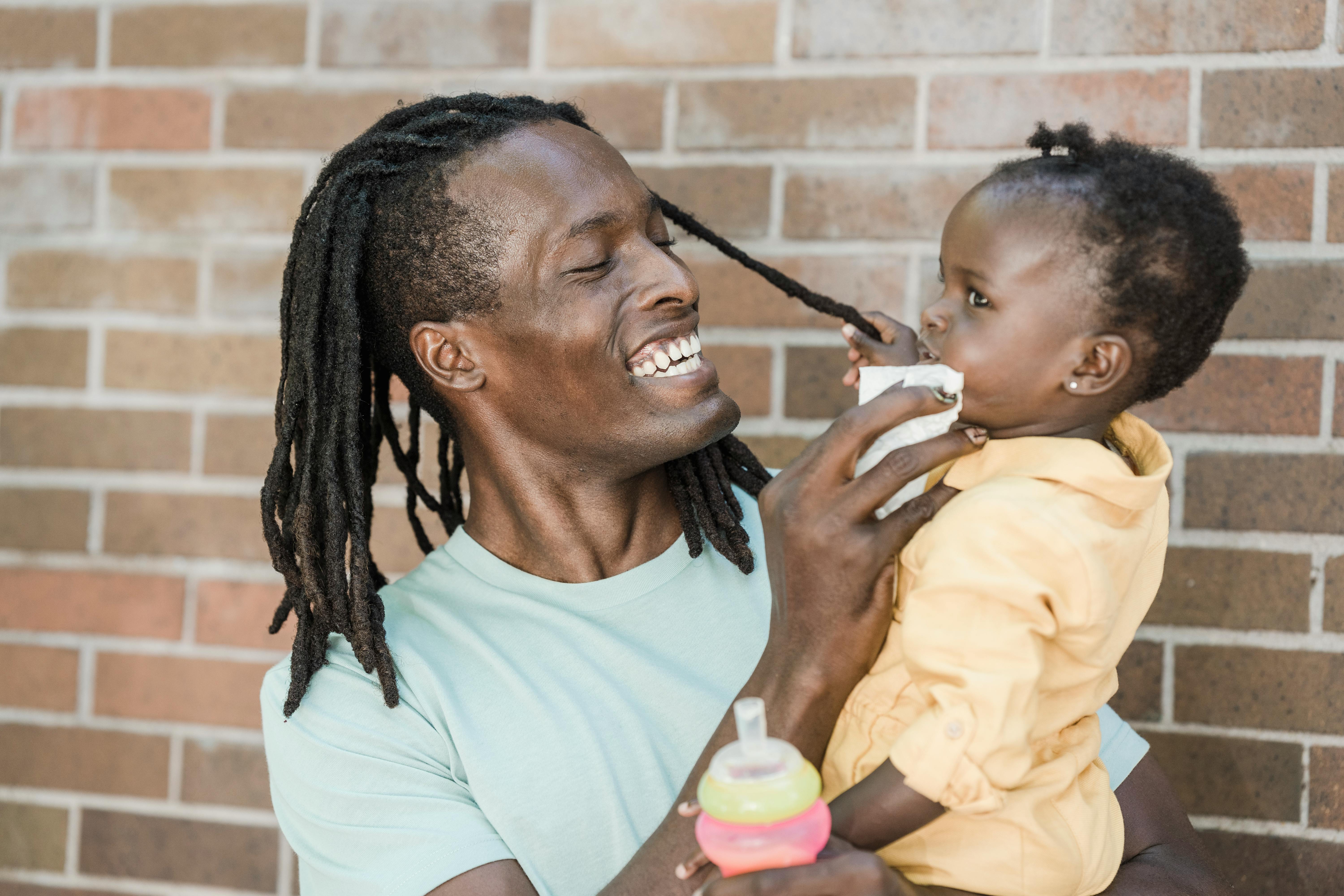 a man smiling wiping his daughter s face