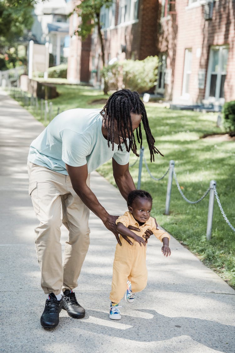 Man And With His Daughter Walking On A Sidewalk