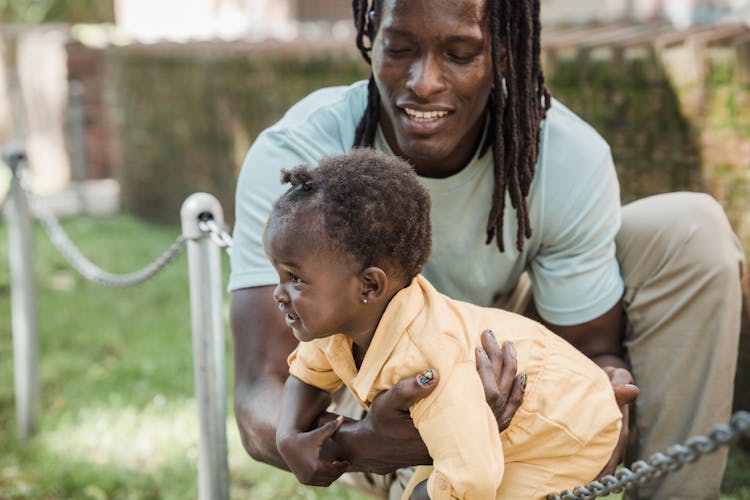 A Man Crouching Carrying A Child In Yellow Jumpsuit