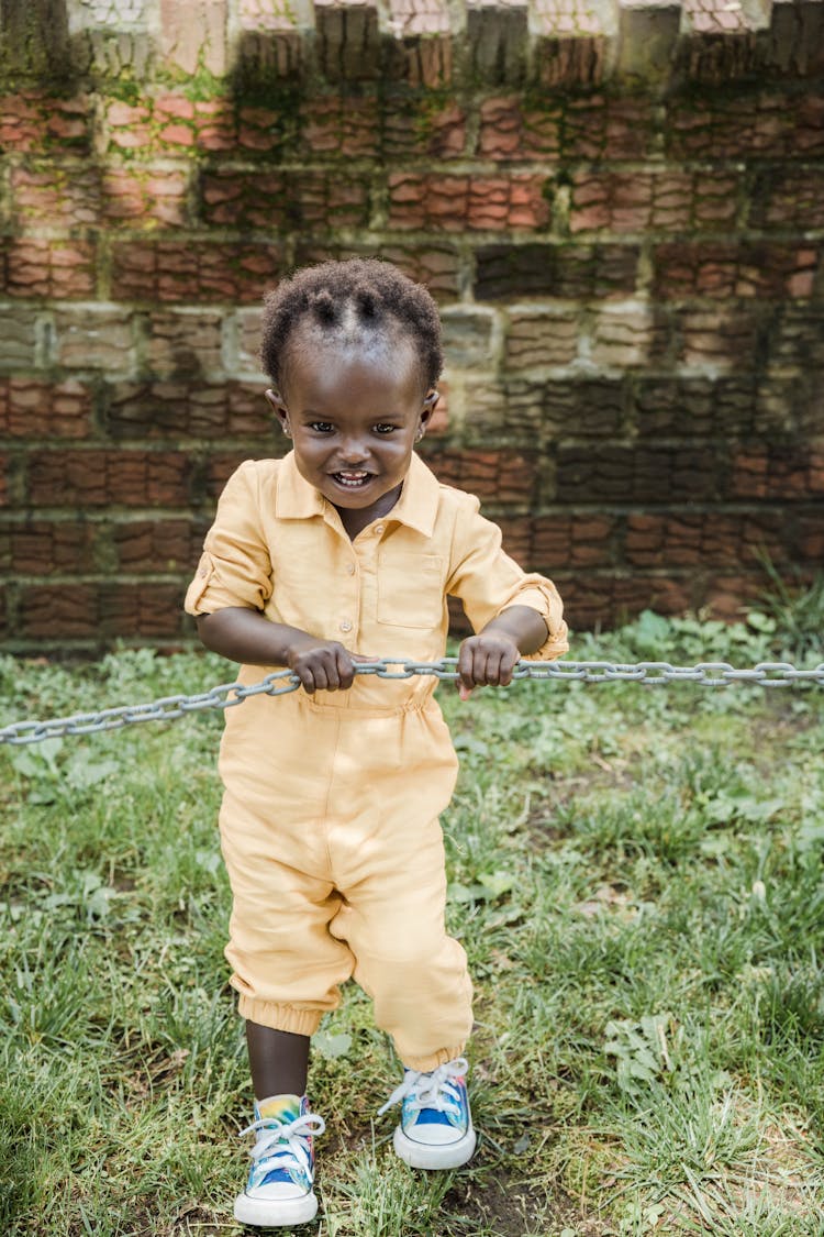 A Girl In Yellow Jumpsuit Holding A Metal Chain