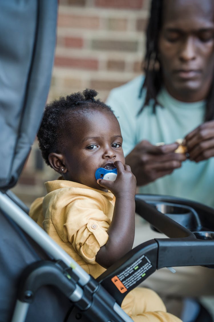 A Child In Yellow Top Holding Her Pacifier