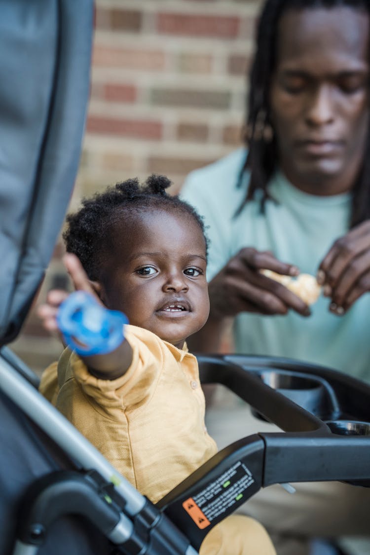 Little Girl Holding A Pacifier In A Walker And Her Dad