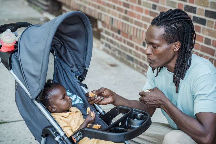 Father Feeding Child In Pram