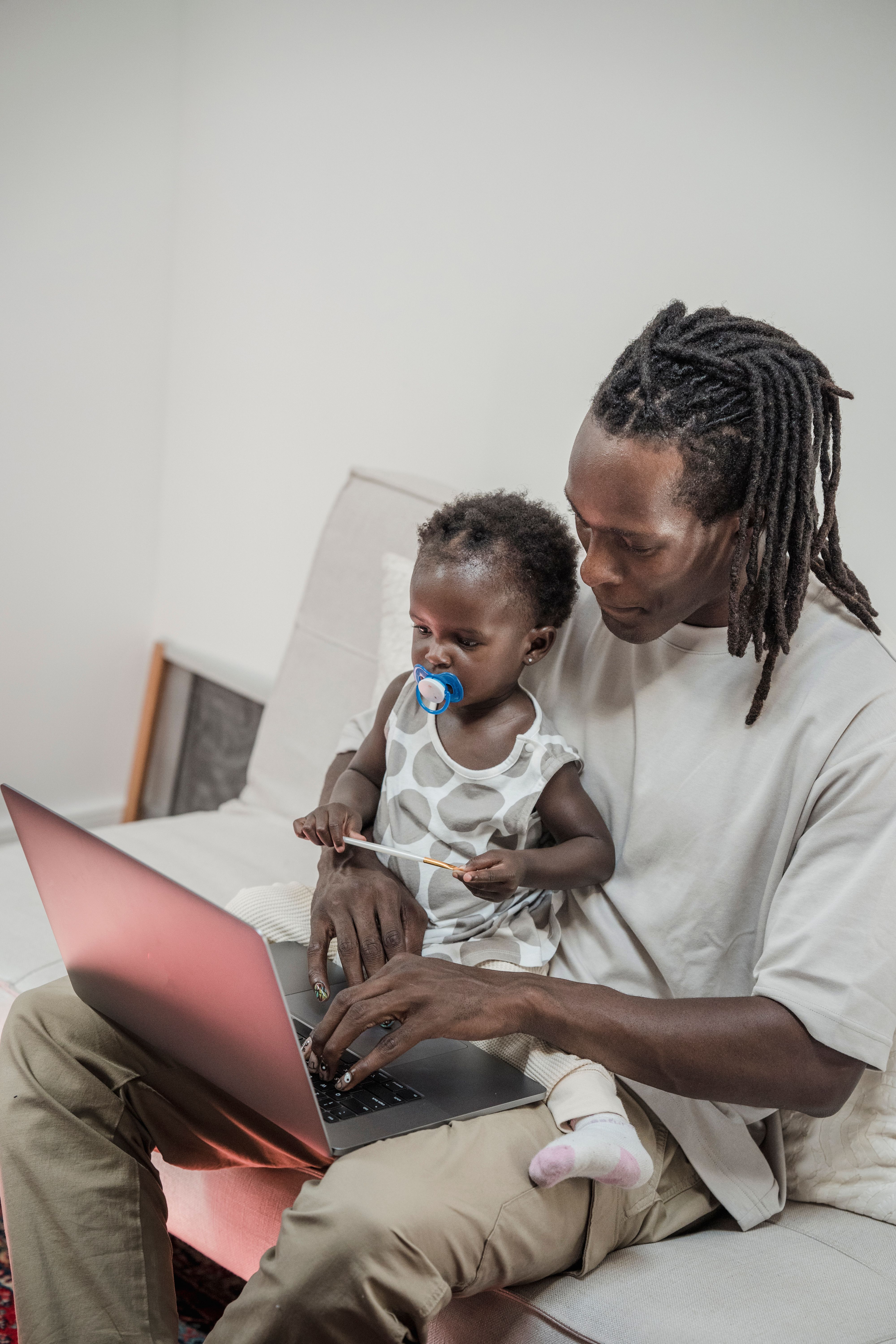 Father and daughter sitting on sofa, enjoying time together with a laptop.