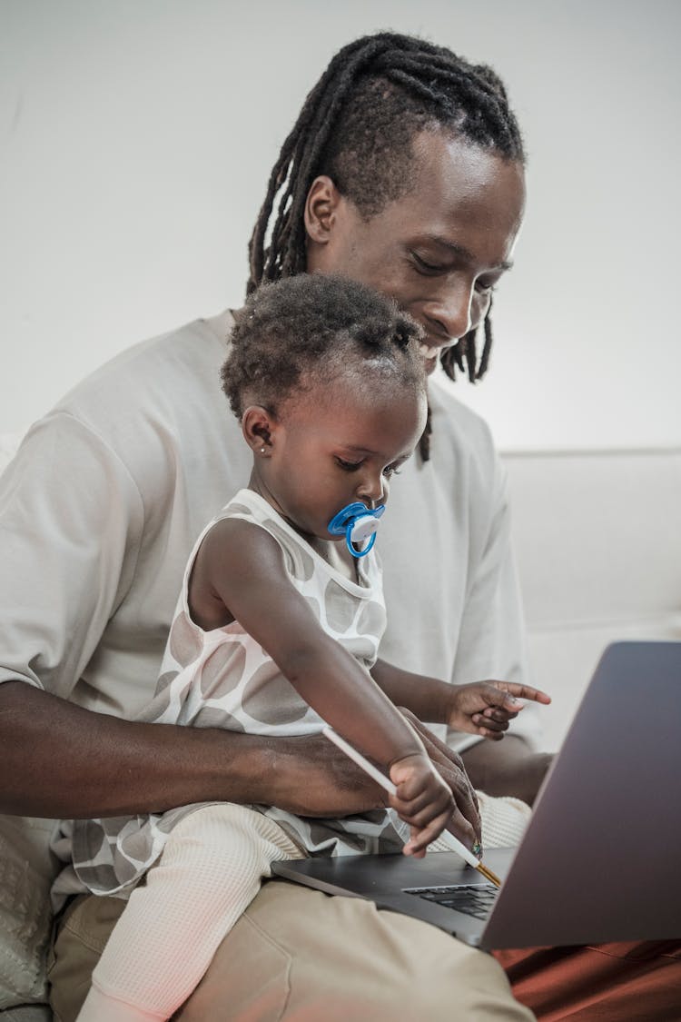 Man In White Shirt Sitting With A Baby While Using Laptop