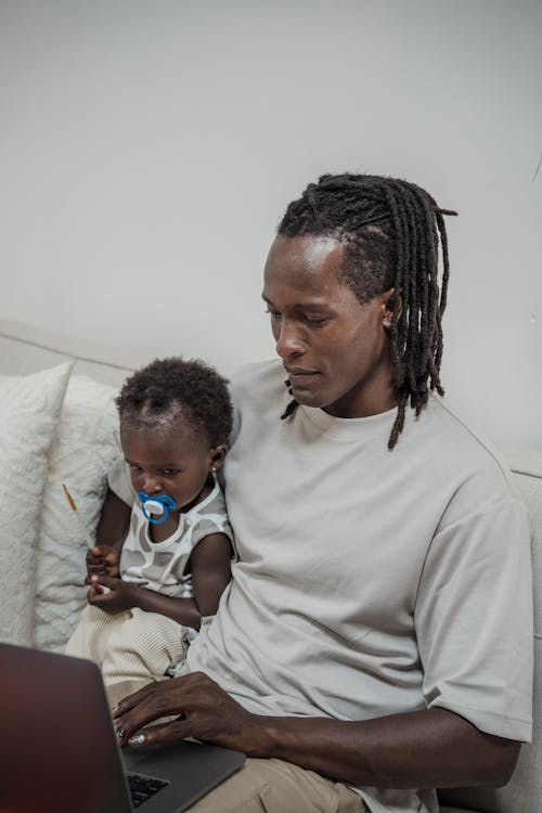 Man Sitting Beside a Child While Using Laptop