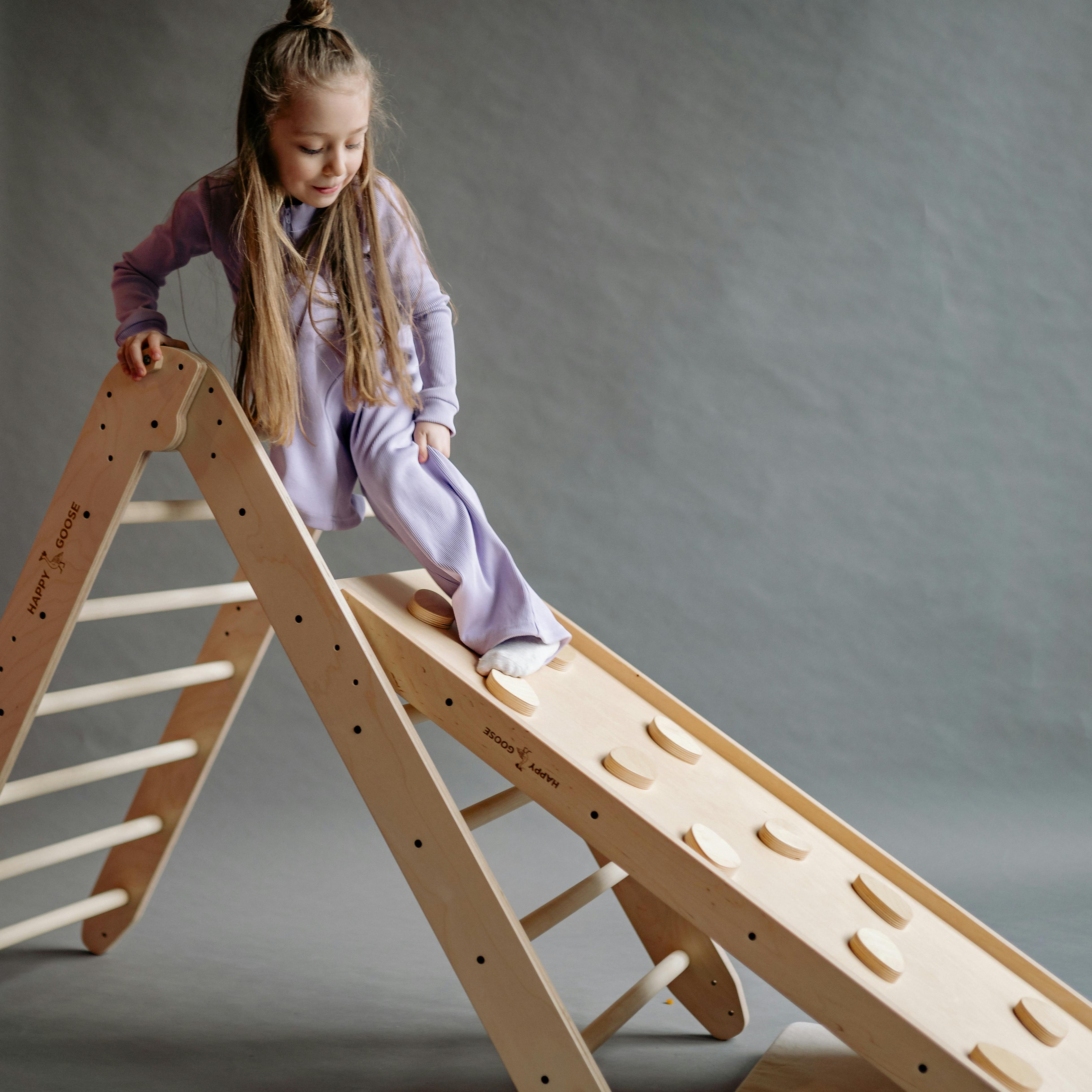 A young girl in lilac pyjamas enjoying a wooden playset indoors. Perfect for playful childhood moments.