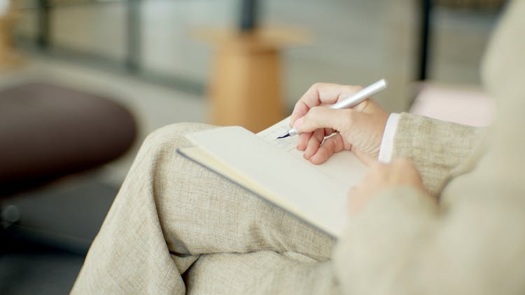 A Person Writing On Notebook