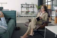 A psychiatrist and patient during a session in a modern office. Calm and professional atmosphere.