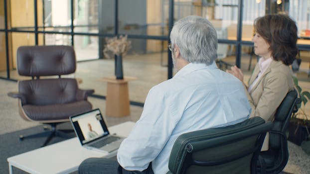 Elderly professionals engaging in an online meeting in a modern office setting.