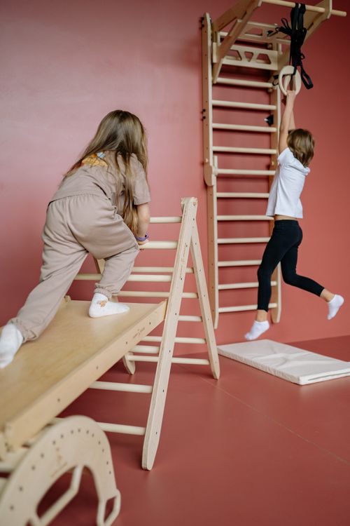 Free Two kids enjoying playtime on wooden climbing structures in an indoor playground. Stock Photo