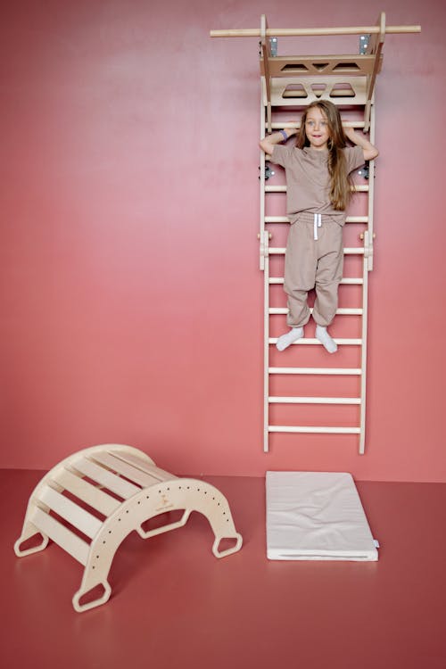 Girl Standing on a Wall Ladder in a Pink Room