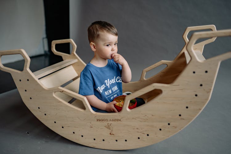 Boy Sitting On A Wooden Seesaw 