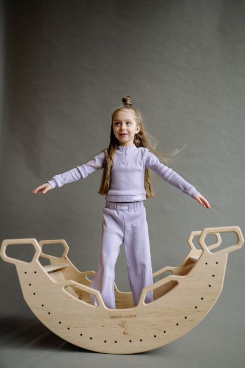Girl balancing on a wooden seesaw toy indoors