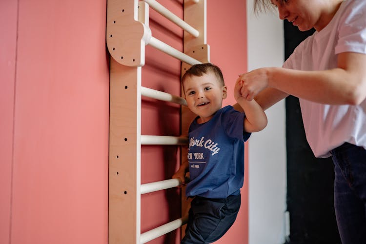 Woman Helping A Boy Climb A Wooden Ladder 