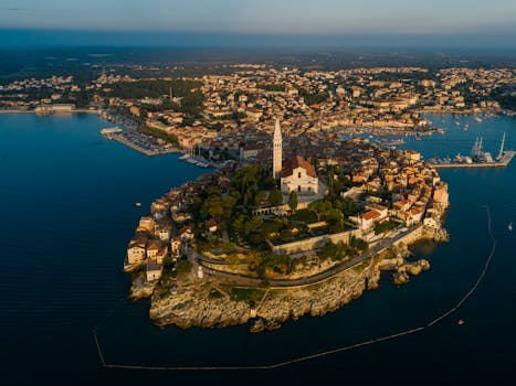 Scenic aerial view of Rovinj's old town and Saint Euphemia Church against the Adriatic Sea at sunset.