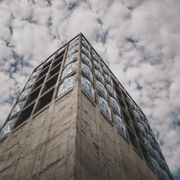 Faceted concrete tower seen from below against broken cloud — photo by Jay jay Redelinghuys on Pexels