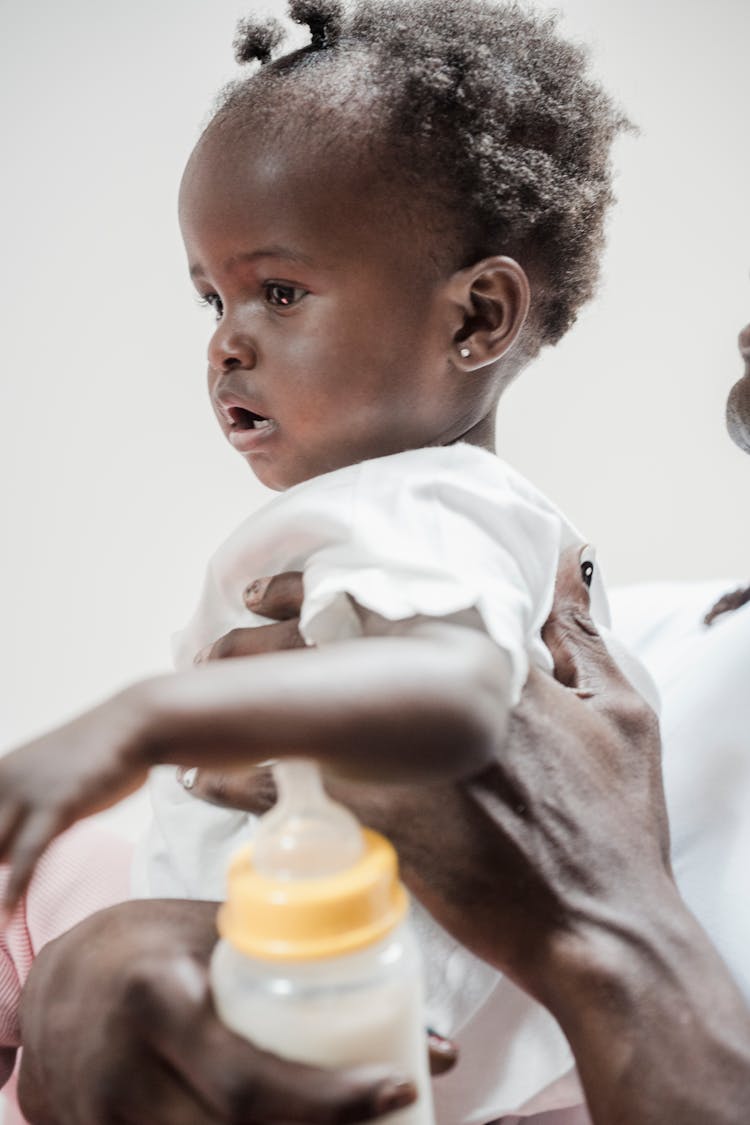 A Person Holding The Baby Up With A Baby Bottle On Hand