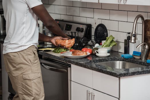 A man prepares breakfast in a modern kitchen with fresh croissants and vegetables.