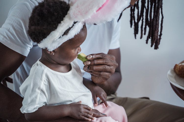 An Adult Feeding A Child